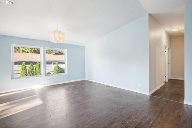 empty room featuring dark hardwood / wood-style flooring and a chandelier