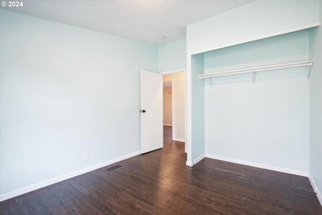 unfurnished bedroom with a textured ceiling, a closet, and dark hardwood / wood-style flooring