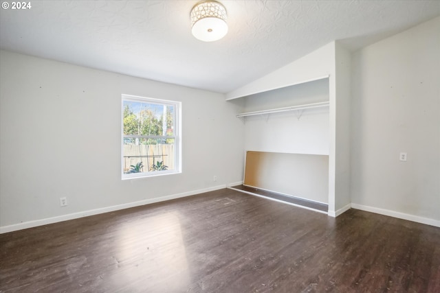 unfurnished bedroom with dark hardwood / wood-style flooring, a closet, vaulted ceiling, and a textured ceiling