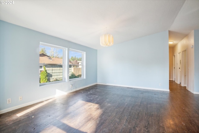 unfurnished room with an inviting chandelier and dark hardwood / wood-style flooring