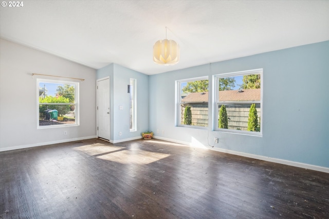 unfurnished room with a wealth of natural light, dark wood-type flooring, a chandelier, and lofted ceiling