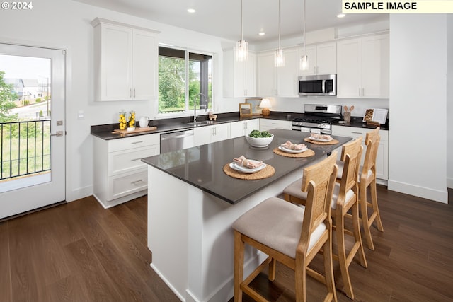 kitchen featuring decorative light fixtures, white cabinetry, dark wood-type flooring, and appliances with stainless steel finishes