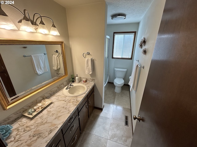 bathroom with tile patterned floors, vanity, a textured ceiling, and toilet