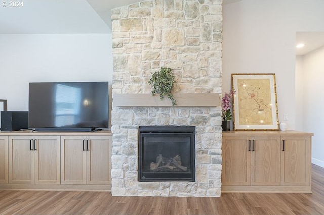 unfurnished living room featuring a fireplace, light hardwood / wood-style floors, and lofted ceiling