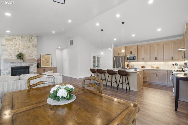 dining area with light hardwood / wood-style floors, lofted ceiling, and a fireplace