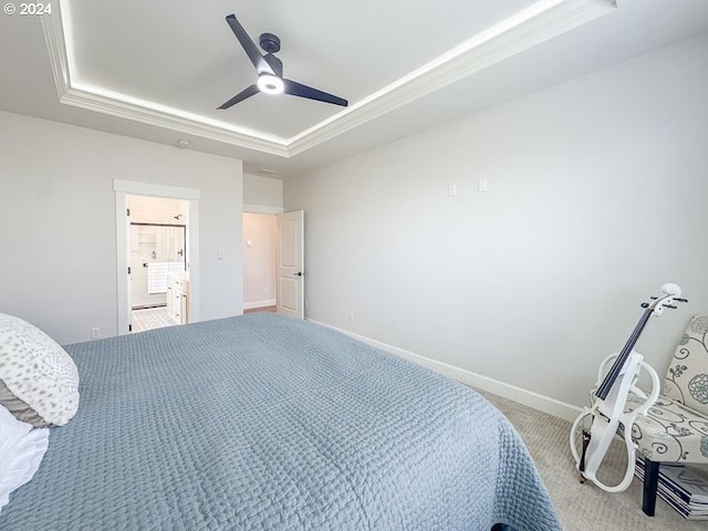 bedroom with ceiling fan, carpet, a tray ceiling, and ensuite bathroom