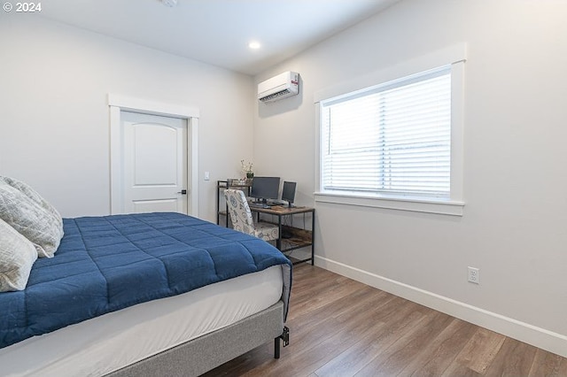 bedroom featuring hardwood / wood-style flooring and a wall mounted AC