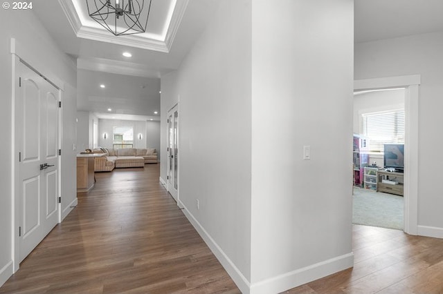 hall with ornamental molding, hardwood / wood-style floors, and an inviting chandelier