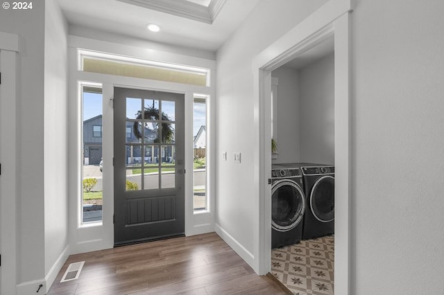 entrance foyer featuring plenty of natural light, hardwood / wood-style flooring, washing machine and dryer, and ornamental molding