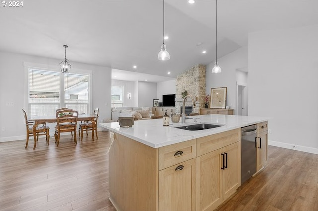 kitchen featuring dishwasher, light brown cabinetry, sink, vaulted ceiling, and a center island with sink