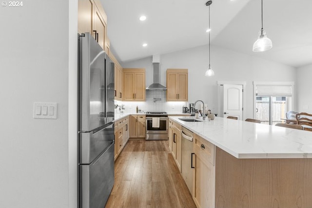 kitchen featuring appliances with stainless steel finishes, sink, wall chimney exhaust hood, tasteful backsplash, and a kitchen island with sink