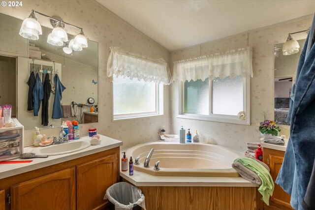 bathroom with vanity, a bath, and vaulted ceiling