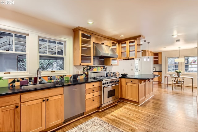 kitchen with sink, light wood-type flooring, appliances with stainless steel finishes, decorative light fixtures, and kitchen peninsula