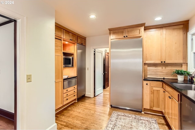 kitchen featuring backsplash, sink, light brown cabinetry, appliances with stainless steel finishes, and light hardwood / wood-style floors