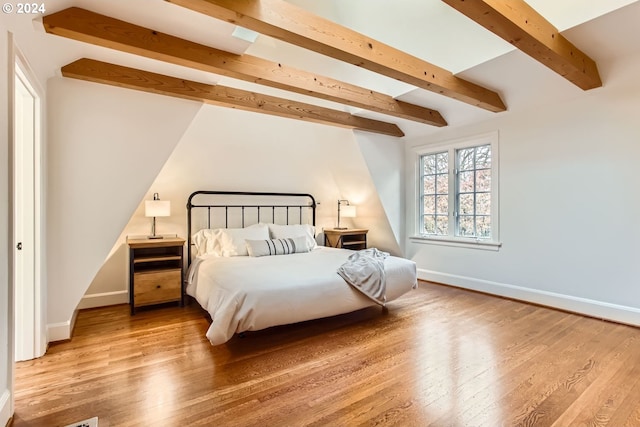 bedroom with beamed ceiling and wood-type flooring