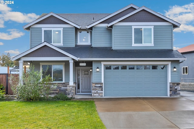 craftsman-style house featuring covered porch, a front yard, and a garage