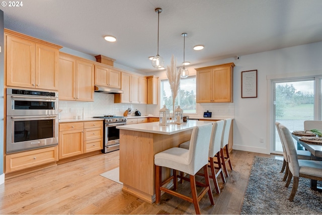 kitchen with decorative light fixtures, light brown cabinetry, light hardwood / wood-style floors, and appliances with stainless steel finishes