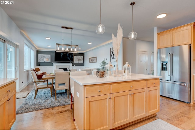 kitchen featuring light hardwood / wood-style flooring, a center island, hanging light fixtures, high end fridge, and light brown cabinets