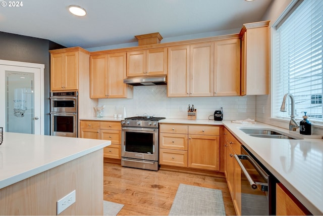 kitchen featuring sink, light wood-type flooring, backsplash, appliances with stainless steel finishes, and light brown cabinets