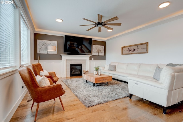 living room featuring ceiling fan, crown molding, a fireplace, and wood-type flooring