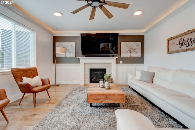 living room with a fireplace, ceiling fan, a wealth of natural light, and light hardwood / wood-style flooring