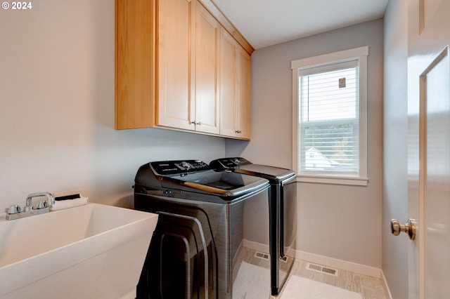 washroom featuring sink, cabinets, a healthy amount of sunlight, and washing machine and dryer