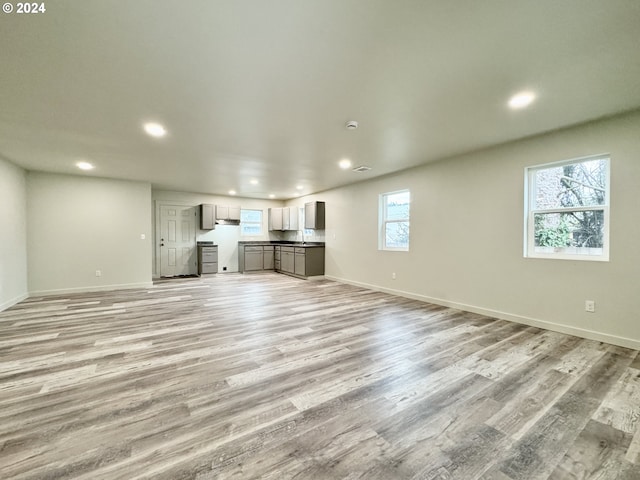 unfurnished living room with light hardwood / wood-style floors and sink