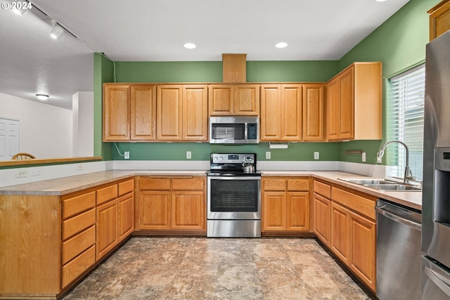 kitchen featuring kitchen peninsula, appliances with stainless steel finishes, track lighting, and sink