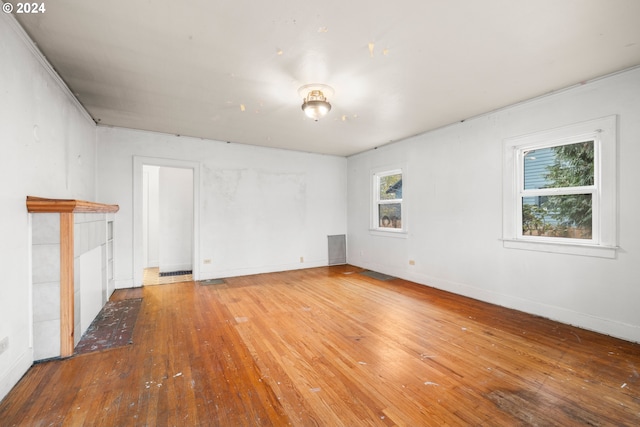 unfurnished room featuring a tile fireplace and wood-type flooring