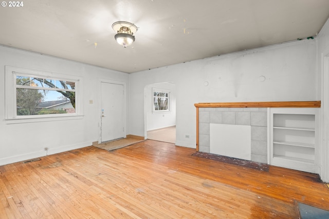 unfurnished living room with a tile fireplace and light hardwood / wood-style flooring