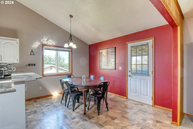 dining area with a notable chandelier and lofted ceiling