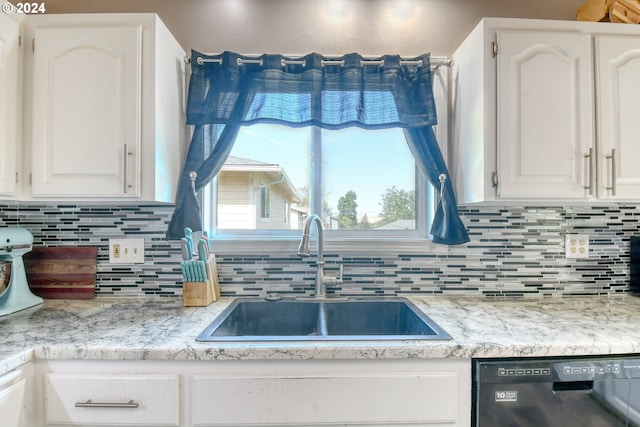 kitchen featuring black dishwasher, sink, decorative backsplash, and white cabinetry