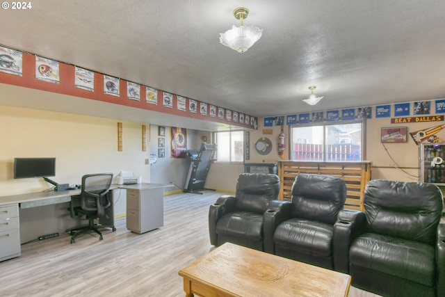 cinema room featuring light wood-type flooring, built in desk, and a textured ceiling