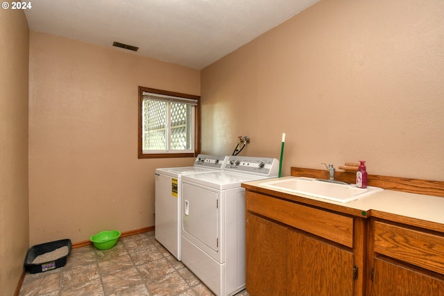 clothes washing area featuring cabinets, sink, and washing machine and clothes dryer