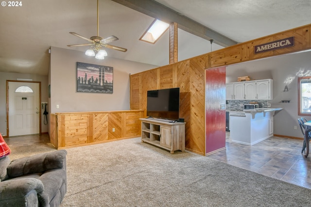 carpeted living room with ceiling fan and lofted ceiling with skylight