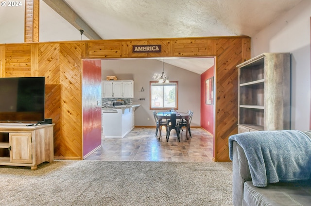 carpeted living room with a notable chandelier, vaulted ceiling with beams, and wood walls