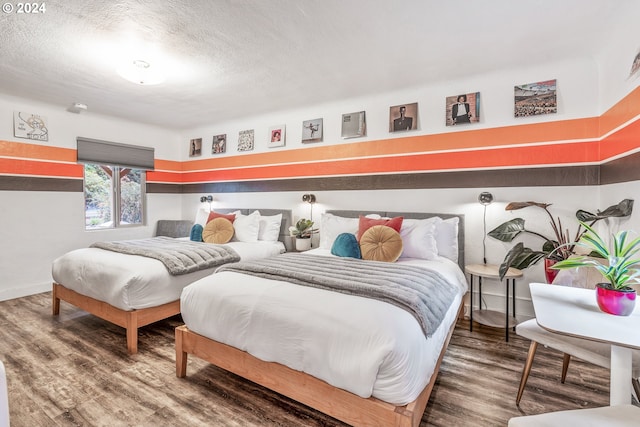 bedroom with wood finished floors, baseboards, and a textured ceiling