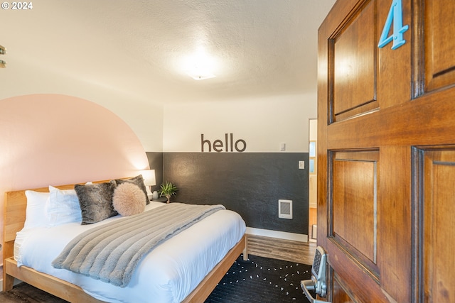 bedroom with wood finished floors, baseboards, and a textured ceiling