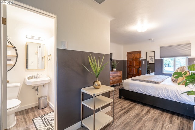 bedroom featuring wood finished floors, a sink, baseboards, and ensuite bathroom