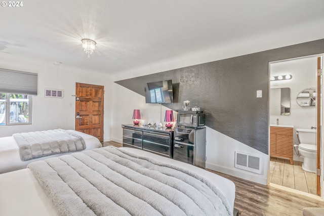 bedroom with wood finished floors and connected bathroom