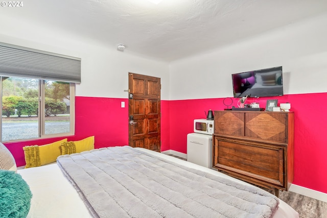 bedroom with wood finished floors, baseboards, and refrigerator