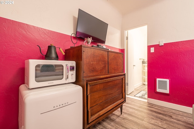 laundry room featuring wood finished floors, heating unit, and a textured wall