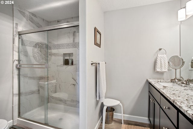 bathroom featuring an enclosed shower, vanity, a textured ceiling, and toilet