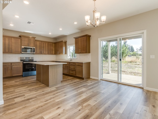 kitchen with sink, decorative light fixtures, a chandelier, appliances with stainless steel finishes, and light hardwood / wood-style floors