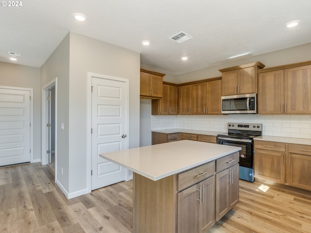 kitchen featuring light hardwood / wood-style flooring, appliances with stainless steel finishes, backsplash, and a center island