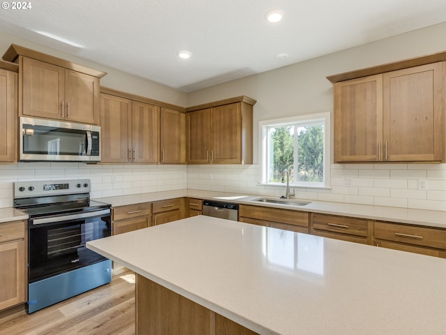 kitchen featuring appliances with stainless steel finishes, sink, light hardwood / wood-style flooring, and tasteful backsplash