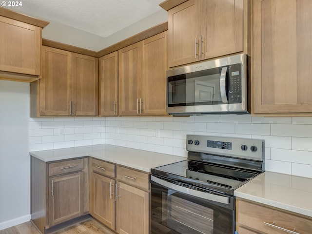 kitchen featuring appliances with stainless steel finishes, light wood-type flooring, and tasteful backsplash