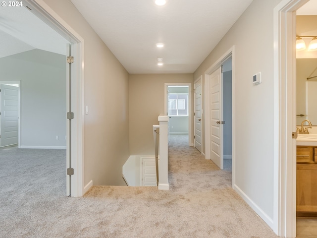 corridor featuring light carpet and sink