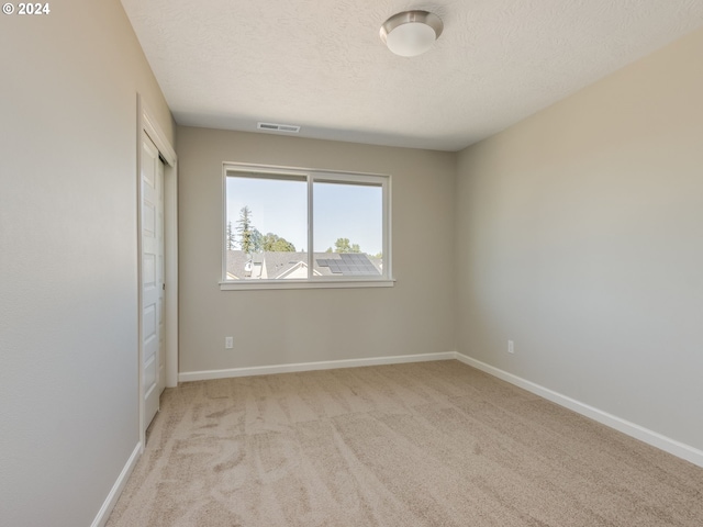 carpeted spare room with a textured ceiling