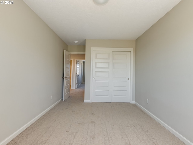 unfurnished bedroom featuring light carpet and a closet